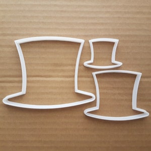 Può includere: Tre tagliabiscotti in plastica bianca a forma di cappello a cilindro. Il tagliabiscotti più grande è al centro, con un tagliabiscotti più piccolo a destra e un tagliabiscotti più piccolo a sinistra.