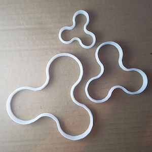 May include: Three white plastic cookie cutters shaped like a fidget spinner. The cutters are different sizes.