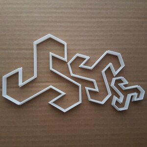 Puede incluir: Un conjunto de cortadores de galletas geométricos blancos de varios tamaños, dispuestos sobre una superficie marrón. Las formas angulares y abstractas son adecuadas para crear productos horneados únicos.