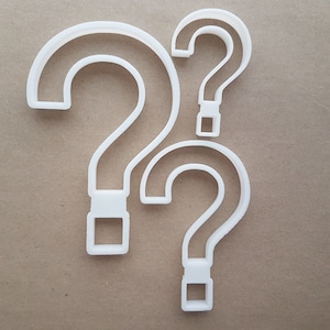 Könnte beinhalten: Drei weiße Plastik-Ausstecher in Form eines Fragezeichens in verschiedenen Größen. Das größte Fragezeichen befindet sich links, das kleinste oben und das mittelgroße Fragezeichen rechts.