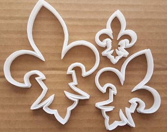 Könnte beinhalten: Drei weiße Plastik-Ausstecher in Form von Fleur-de-lis.