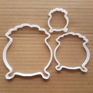 Könnte beinhalten: Drei weiße Plastik-Ausstecher in Form von Kesseln. Der größte Kessel ist etwa 12,5 cm breit, der mittlere Kessel ist etwa 7,5 cm breit und der kleinste Kessel ist etwa 5 cm breit.