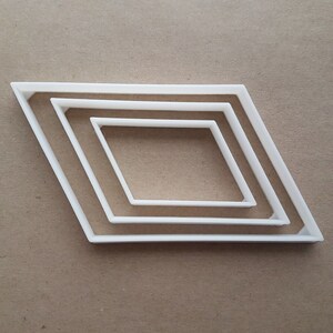 Può includere: Tre tagliabiscotti a forma di diamante di diverse dimensioni, in plastica bianca.