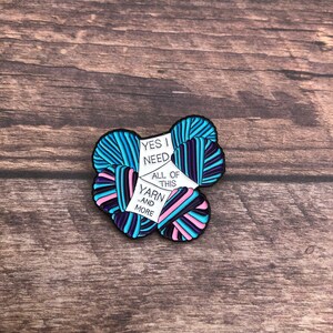 May include: A colorful enamel pin featuring a pile of yarn with the text "Yes I need all of this yarn...and more".