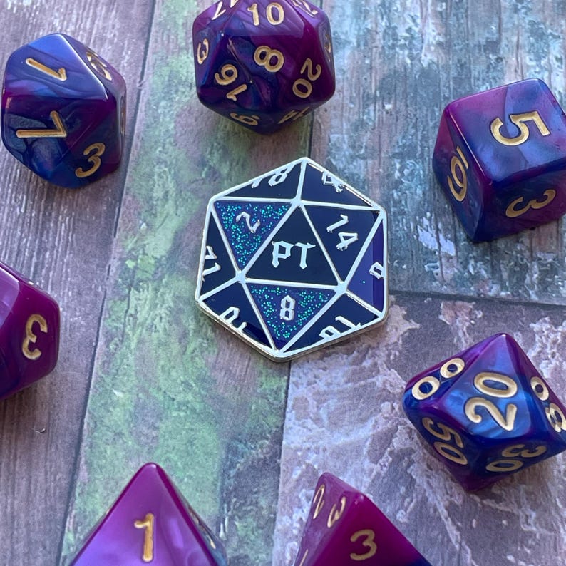 May include: A collection of purple and blue dice with gold accents. The dice are a variety of shapes and sizes. One die is a 20-sided die with the numbers 10, 8, 16, and 20 visible. Another die is a 6-sided die with the number 3 visible. A third die is a 12-sided die with the number 5 visible. A fourth die is a 4-sided die with the number 3 visible. A fifth die is a 20-sided die with the numbers 00, 20, 50, and 30 visible. A sixth die is a 20-sided die with the number 1 visible. A seventh die is a 14-sided die with the numbers 2, 14, and 8 visible. The 14-sided die has the text "PT" on it.