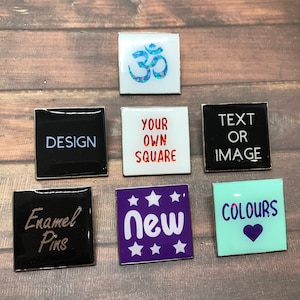 May include: Assortment of enamel pins with various designs.  The pins feature a white om symbol, the words "Your Own Square", "Text or Image", "Enamel Pins", "New", and "Colours".