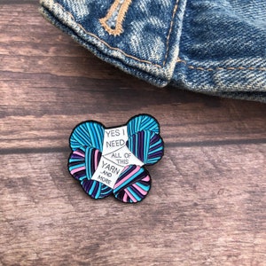 May include: A colorful enamel pin featuring a cluster of yarn balls with the text "Yes I need all of this yarn and more".