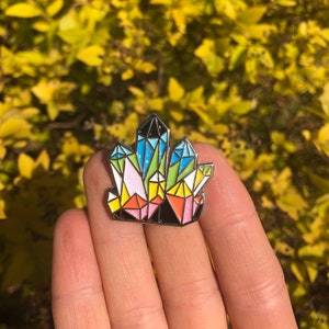 Peut inclure: Une épingle en émail colorée en forme de cristal avec un arc-en-ciel de couleurs, y compris le rose, le bleu, le vert, le jaune et le blanc.