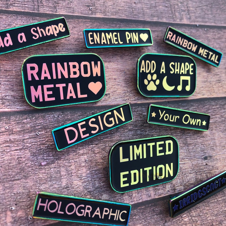 Peut inclure: Une collection d'&eacute;pingles en &eacute;mail avec diff&eacute;rents motifs et textes, notamment "Rainbow Metal", "Add a Shape", "Design", "Limited Edition", "Holographic", "Irridescent", "Enamel Pin", et "Your Own".