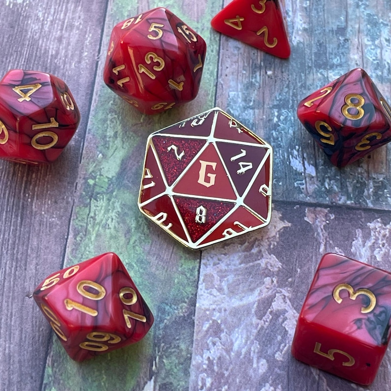 May include: A set of red and gold dice with black numbers. The dice are in a variety of shapes, including a standard six-sided die, a twenty-sided die, and a d8. The dice are on a wooden surface.