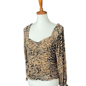 May include: A brown and black animal print long-sleeved blouse with a gathered detail at the waist.