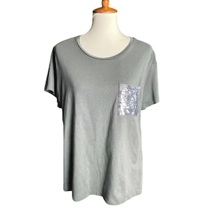 May include: A short-sleeved, olive green t-shirt with a silver sequined pocket.