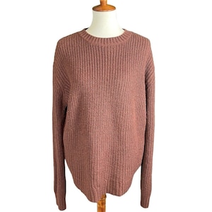 Puede incluir: Un suéter de punto color malva con mangas largas y cuello redondo.