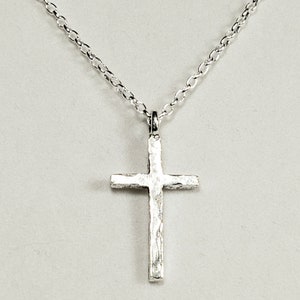 May include: A silver chain necklace with a textured silver cross pendant.