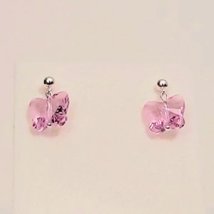 May include: A pair of silver butterfly earrings with pink crystal accents.