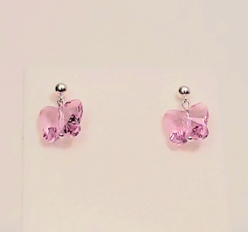 May include: A pair of silver butterfly earrings with pink crystal accents.
