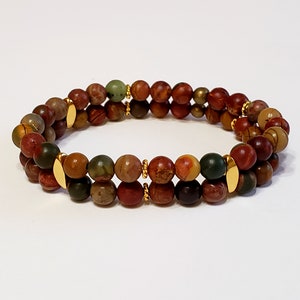 May include: A double-strand bracelet made with brown, red, and green jasper beads and gold accents.