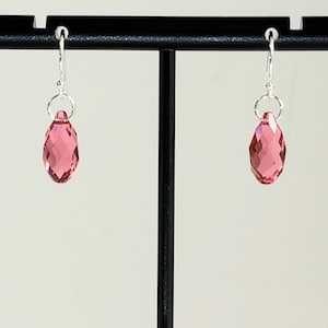May include: A pair of silver earrings with pink crystal teardrop dangles.
