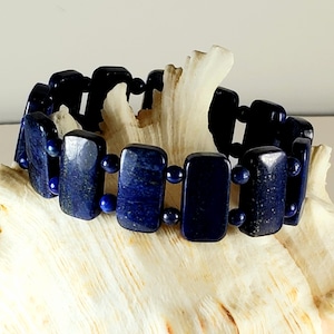 May include: A dark blue lapis lazuli bracelet with rectangular beads separated by smaller round beads.