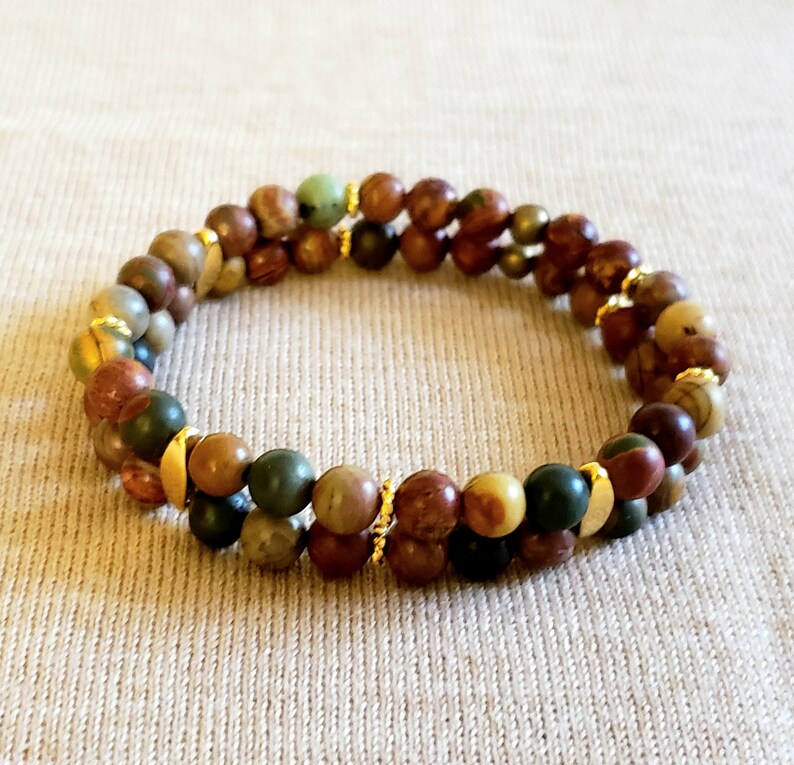 May include: A double-strand bracelet with brown, green, and gold beads. The beads are made of natural stone and are separated by gold spacers.