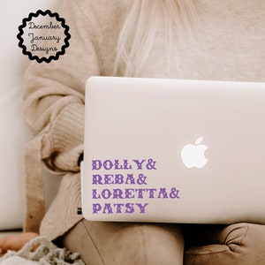 May include: A white laptop with a purple vinyl sticker that says "DOLLY & REBA & LORETTA & PATSY" on the back of the laptop.