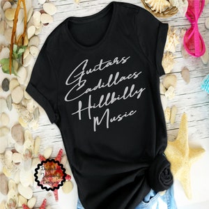 Puede incluir: Camiseta negra con el texto "Guitars Cadillacs Hillbilly Music" en una fuente blanca cursiva.