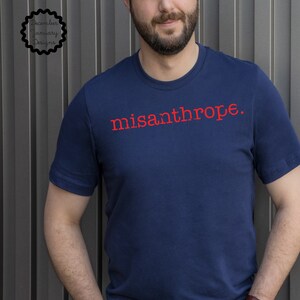 May include: A navy blue t-shirt with the word "misanthrope" printed in red on the front.