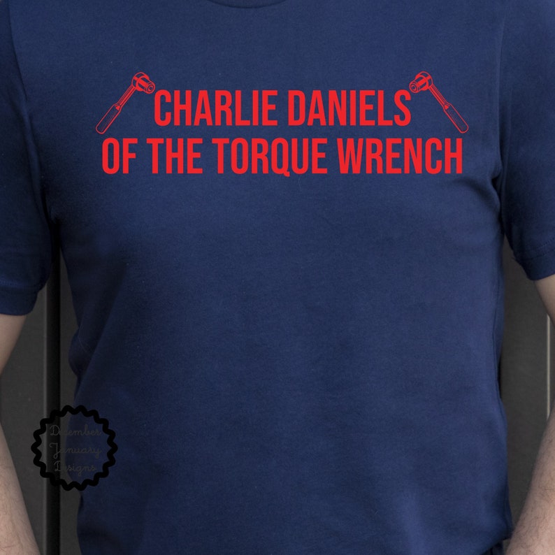 May include: A navy blue t-shirt with red text that reads "Charlie Daniels of the Torque Wrench" and two red wrench illustrations.