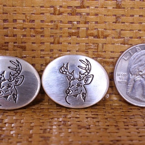 May include: Three silver-toned metal tokens with a deer head design. The deer head is outlined in black and has antlers. The tokens are about the size of a US quarter.
