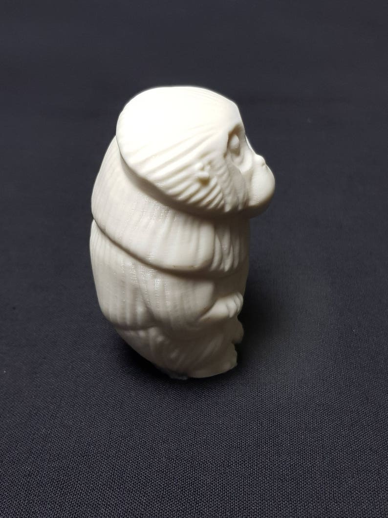 May include: A white ceramic figurine of a monkey sitting with its head tilted to the side.