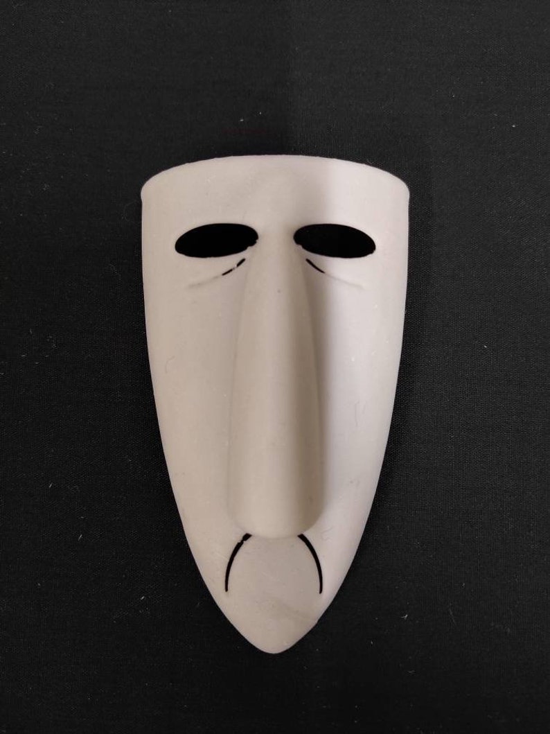 May include: White mask with a long, thin nose and black eyes. The mask has a slight frown.