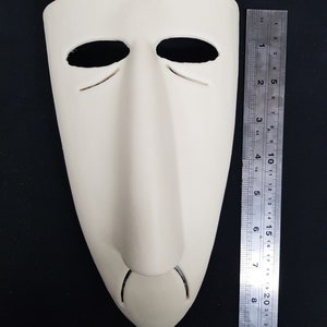 May include: A white plaster mask with a long, thin nose and two eye holes. The mask is about 7 inches tall.