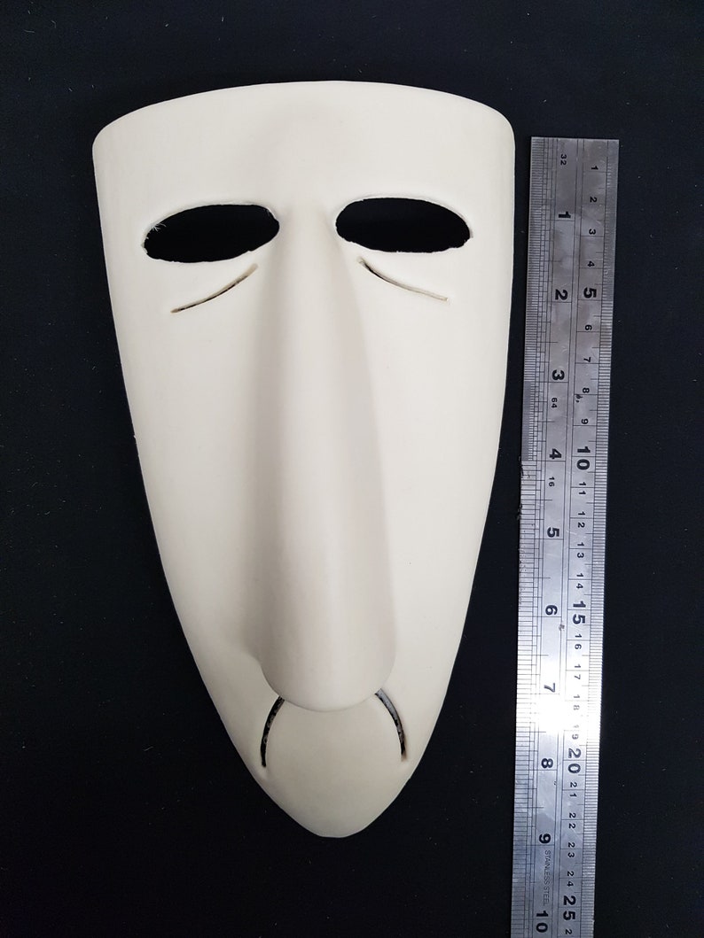 May include: A white plaster mask with a long, thin nose and two eye holes. The mask is about 7 inches tall.