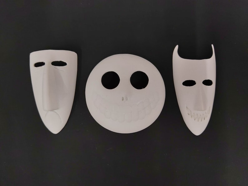 May include: Three white ceramic masks with different facial expressions. The masks are all in the shape of a human face, but each has a unique design. The first mask has a long nose and a sad expression. The second mask has a wide smile and two large eyes. The third mask has a pointed chin and a mischievous expression.