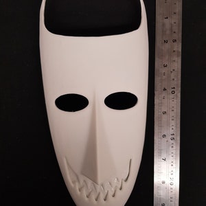 May include: White plastic mask with a pointed top and a wide, toothy grin. The mask is about 7 inches tall.
