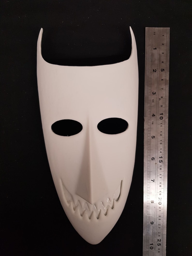 May include: White plastic mask with a pointed top and a wide, toothy grin. The mask is about 7 inches tall.