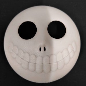 May include: A white 3D printed mask with a wide smile and two black eye holes. The mask is a popular Halloween decoration.