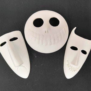 Puede incluir: Tres máscaras de cerámica blanca con diferentes expresiones faciales. Las máscaras tienen todas la forma de un rostro humano, pero con rasgos exagerados. La primera máscara tiene una amplia sonrisa con dientes, la segunda máscara tiene una expresión neutral y la tercera máscara tiene el ceño fruncido.