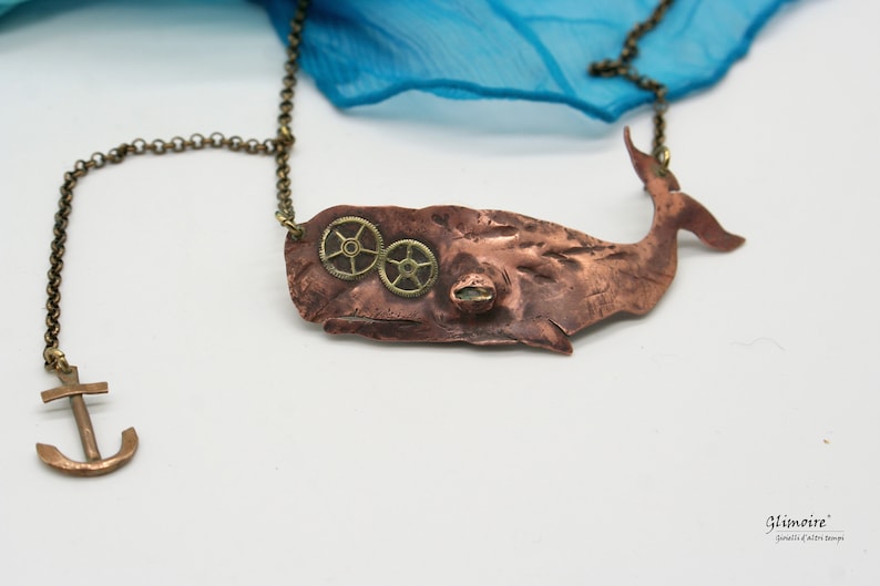 May include: A copper whale pendant necklace with brass gears and an anchor charm. The whale is textured and has a steampunk aesthetic.