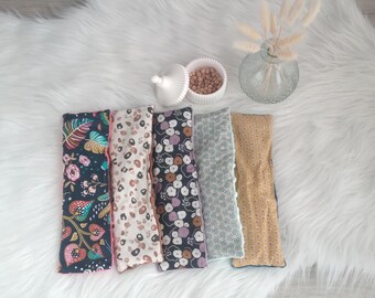 May include: Five fabric pouches with different patterns. The pouches are all rectangular and have a pink seam around the edges. The patterns include floral, geometric, and abstract designs.