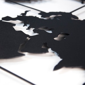 May include: A black metal world map wall decor with a cutout design. The map is mounted on a white background.