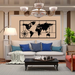 May include: A black metal world map wall decor with a compass design, hanging above a white sofa with blue pillows and a chessboard on a coffee table.