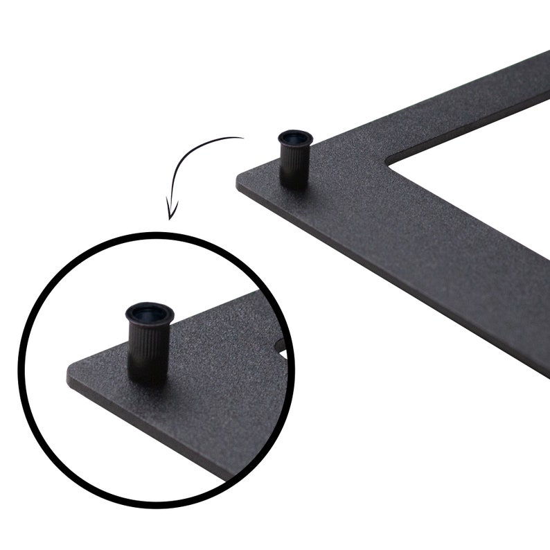 May include: Close-up of a black metal frame with two small black plastic caps. The caps are used to attach the frame to a wall.