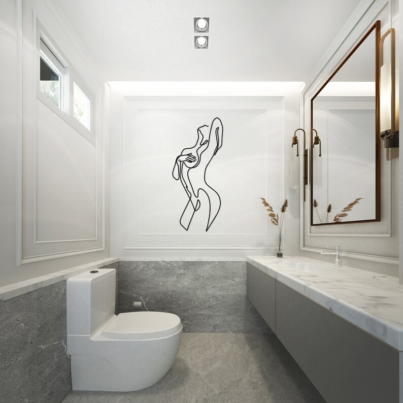 May include: A white toilet with a closed lid in a modern bathroom with a marble countertop and a large mirror. A black line drawing of a woman is on the wall above the toilet.