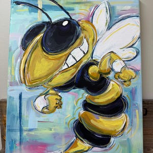 May include: A vibrant painting of a smiling cartoon bee with yellow and black stripes, white wings, and large black eyes. The background features a colorful abstract design with blue, pink, and yellow brushstrokes. The artist's signature and the number 25 are visible.