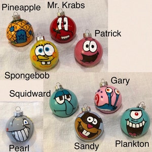 Op de afbeelding: Een verzameling handgeschilderde kerstballen met personages uit een populaire animatieserie. De ornamenten omvatten SpongeBob, Patrick, Octo Tentakel, Mr. Krabs, Sandy, Plankton, Gary en Pearl. Elk ornament heeft een andere kleur en een uniek ontwerp.