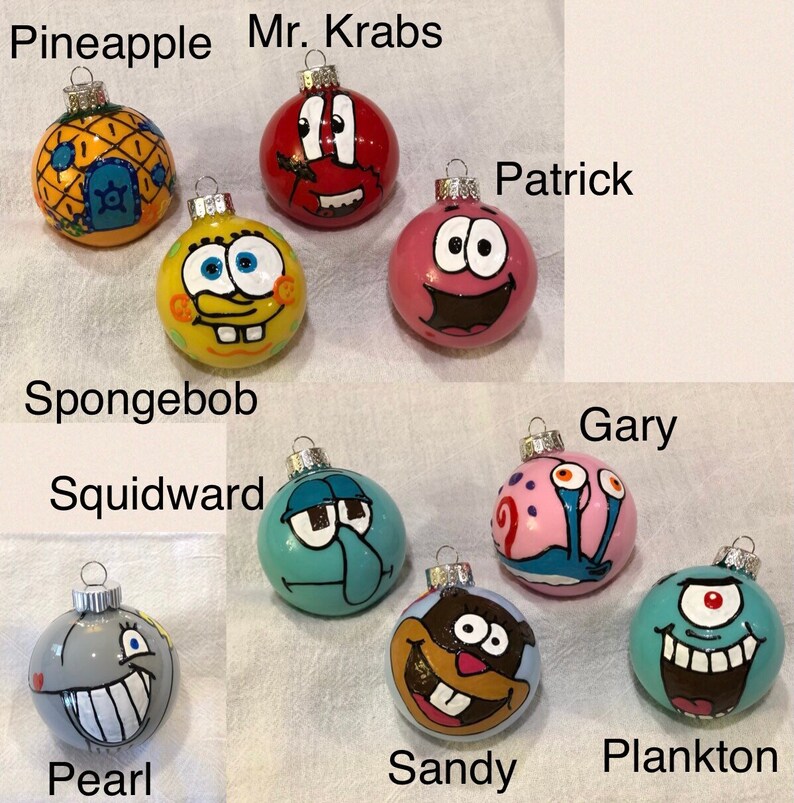 Op de afbeelding: Een verzameling handgeschilderde kerstballen met personages uit een populaire animatieserie. De ornamenten omvatten SpongeBob, Patrick, Octo Tentakel, Mr. Krabs, Sandy, Plankton, Gary en Pearl. Elk ornament heeft een andere kleur en een uniek ontwerp.