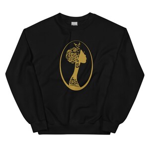 May include: Black sweatshirt with a gold silhouette of a woman's head with intricate hair design inside an oval.