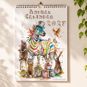 Pode incluir: Um calendário de parede intitulado Animal Calendar 2027 com uma ilustração em aguarela de uma zebra coberta por salpicos de tinta colorida, rodeada por um urso, uma preguiça, coelhos e um pássaro a interagir com baldes de tinta.