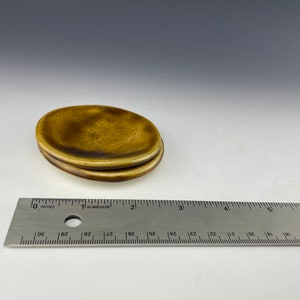 One 3” amber ceramic plate A129